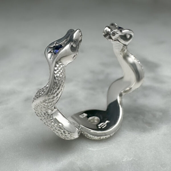silver ring with two entwined snakes with engraved scales and sapphires set into their heads