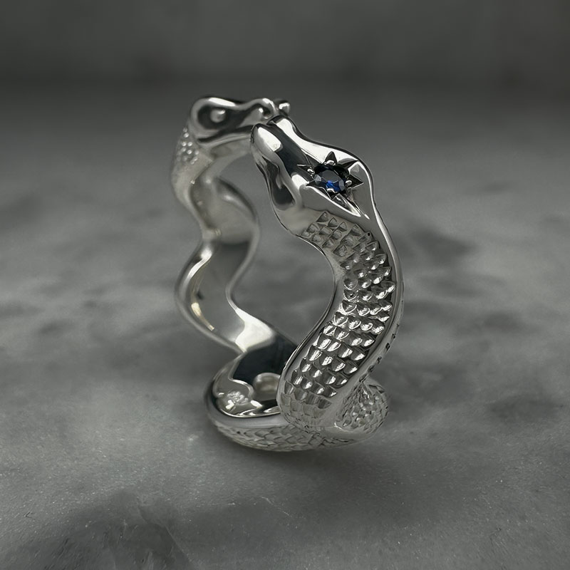 silver ring with two entwined snakes with engraved scales and sapphires set into their heads