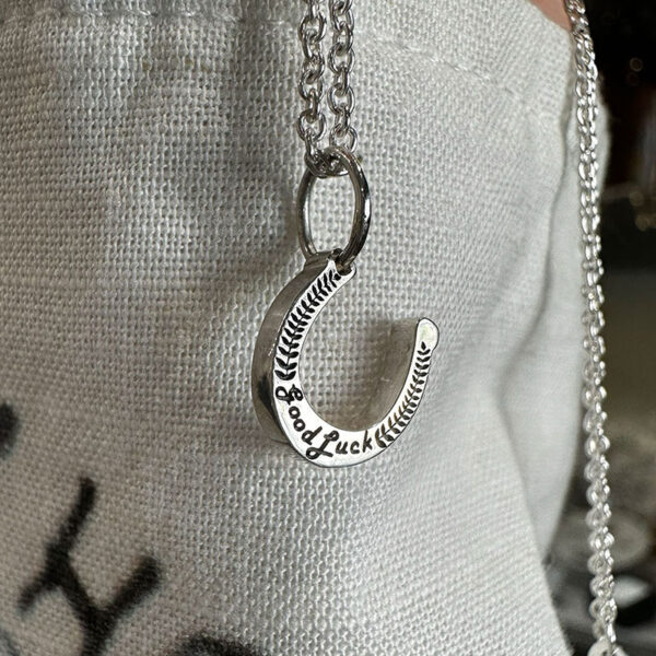 small sterling silver horseshoe charm with "good Luck" embossed on the front with a laurel leaf design